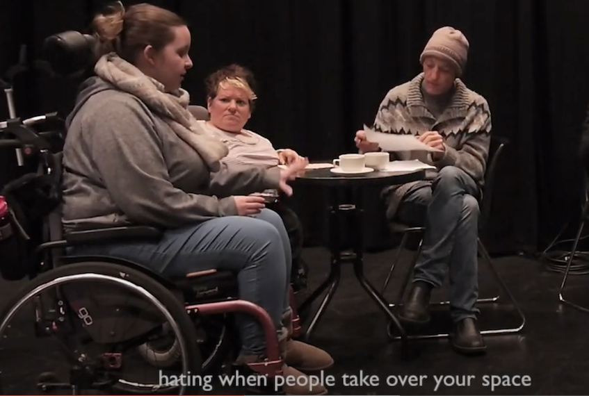 Woman in wheelchair talking to woman and man in beanie, seated around a small round table.